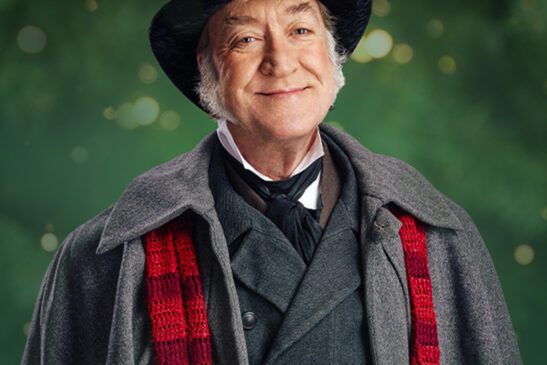 A smiling Scrooge with a caption that reads “holiday joy: past, present, future”