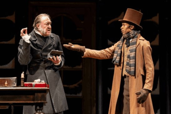 Scrooge and Bob Crachit wear Dicken's era coats and top hats.