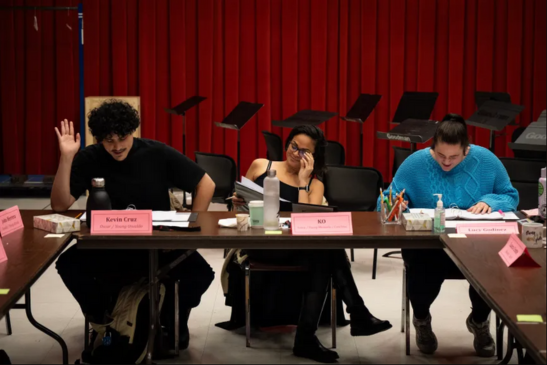 Three people sit at a long table for a New Stages reading.