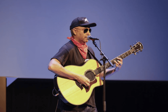 Tom Morello singing and playing a guitar.